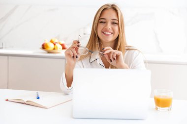 Laptop ve günlükle çalışan mutlu sarışın kadının fotoğrafı.