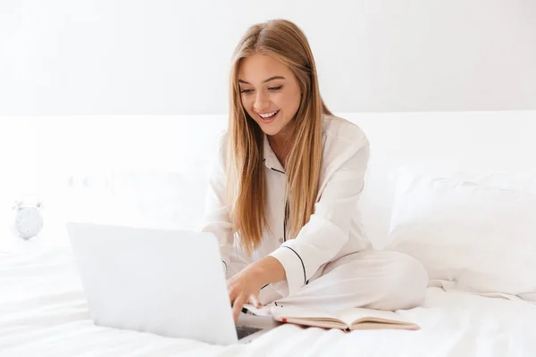 Foto de jovem mulher alegre digitando no laptop e sorrindo — Fotografia de Stock