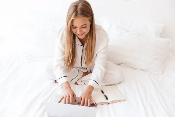 Foto di donna gioiosa bionda che digita sul computer portatile e sorride — Foto Stock