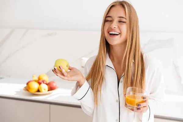 Foto de mulher atraente rindo segurando maçã e bebendo suco — Fotografia de Stock