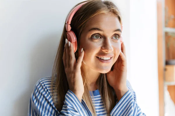 Imagen de una joven escuchando música con auriculares en apartm —  Fotos de Stock