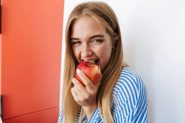 Cheerful lady eating apple in kitchen — 图库照片