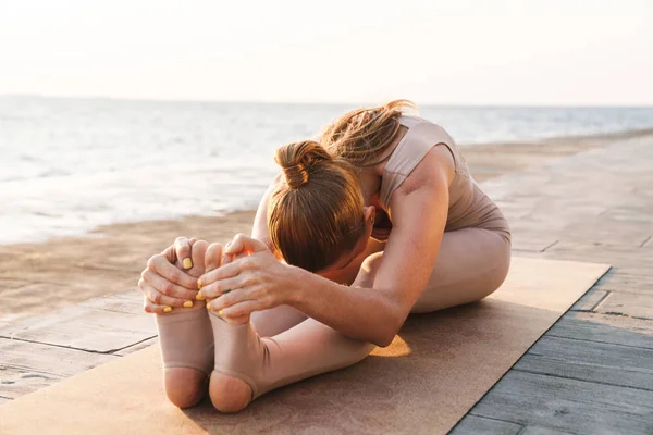 Mooie vrouw buiten op het strand maken stretching oefening. — Stockfoto