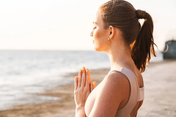 Fitness vrouw mediteren buiten op het strand. — Stockfoto