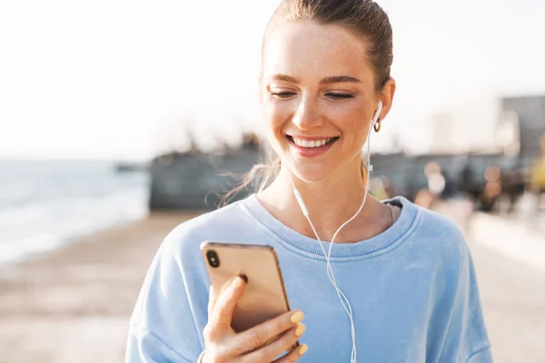 Pozytywna młoda fitness kobieta na świeżym powietrzu słuchanie muzyki — Zdjęcie stockowe