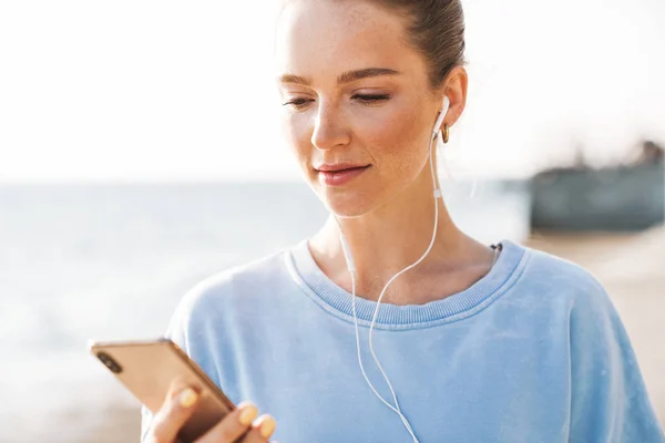 Geconcentreerde fitnessvrouw die muziek luistert met oortjes. — Stockfoto