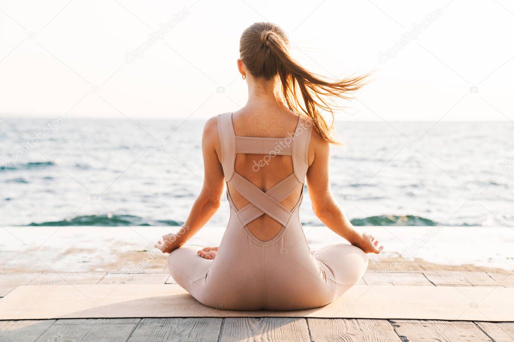 Fitness woman meditate outdoors on beach.