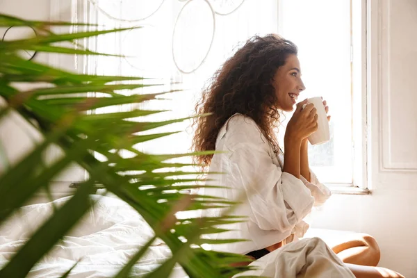 Imagem da jovem caucasiana bebendo chá na cama em apar branco — Fotografia de Stock