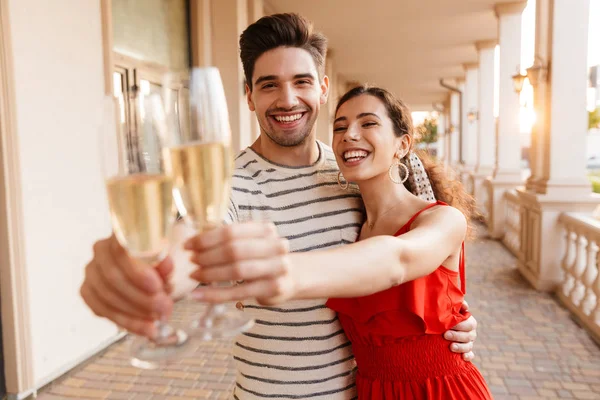 Bild eines lachenden kaukasischen Paares, das sich umarmt und Champagner trinkt — Stockfoto