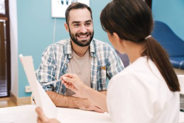 Sağlık sonuçlarına bakan kadın doktor ve hasta adamın görüntüsü