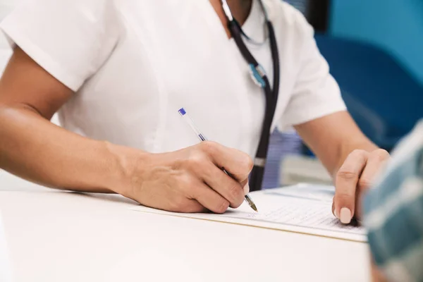 Medico che scrive la ricetta per il paziente in ospedale a tavola . — Foto Stock