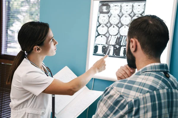 Bild av kvinnlig läkare och patient man tittar på röntgen scan i — Stockfoto