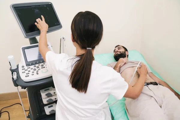 Image of young man getting abdominal ultrasound scan by female d — Stock Image Image of young man getting abdominal ultrasound scan by female d Royalty Free Stock Photos
