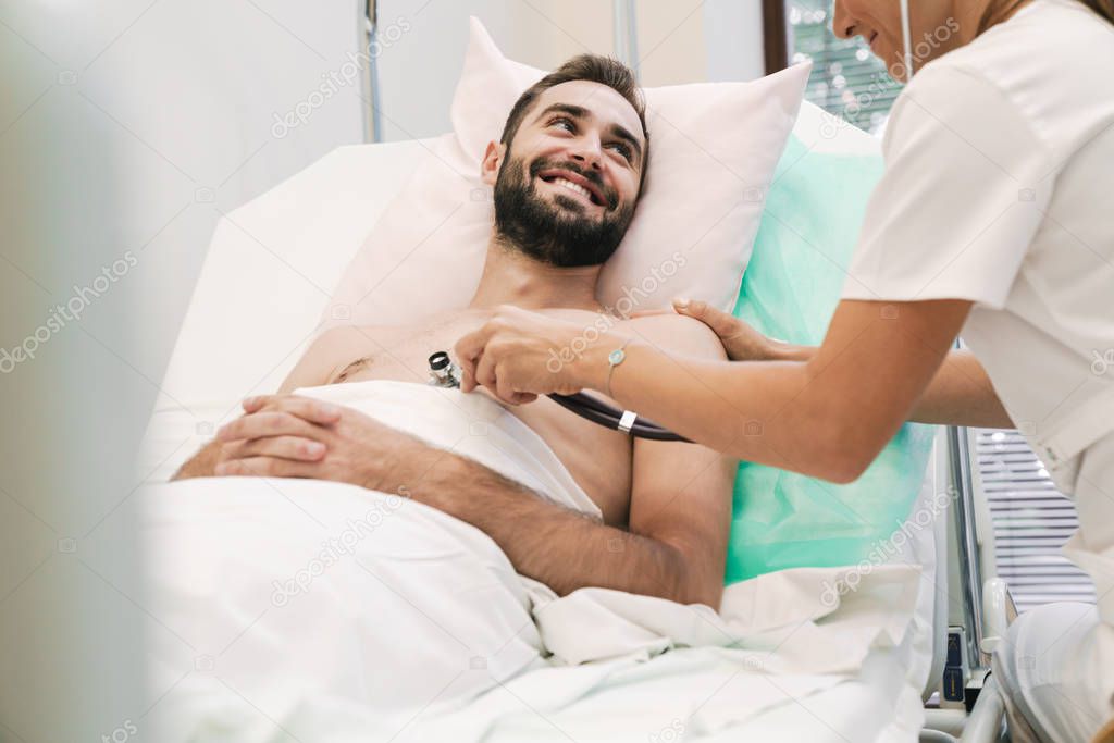 Image of female doctor examining young patient man in hospital b