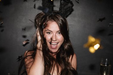 Gülümserken elinde şampanya kadehi tutan mutlu bir kadın resmi