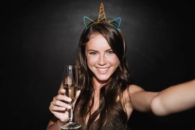 Selfie çekerken elinde cam olan sevimli, gülümseyen bir kadın resmi