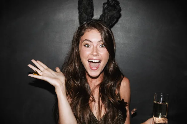 Image of young delighted woman holding glass of champagne while smiling — Stock Photo, Image