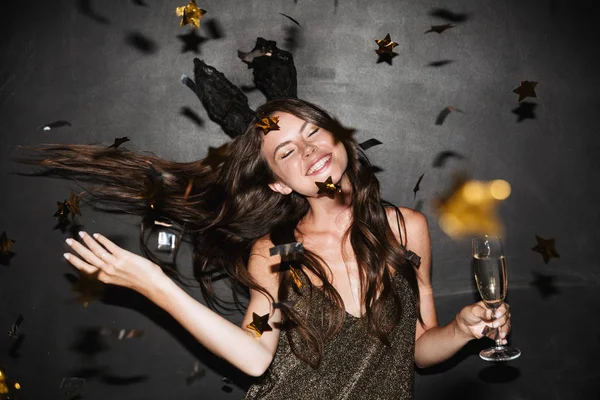 Imagem de uma mulher sorridente segurando um copo de champanhe enquanto dança — Fotografia de Stock