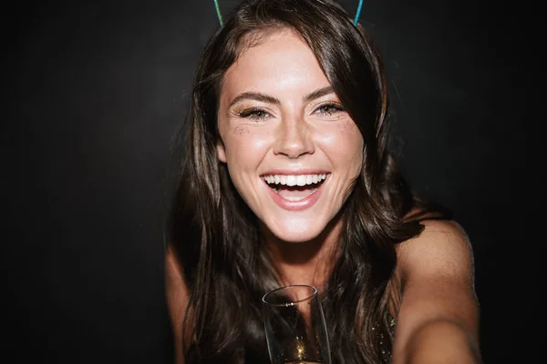 Afbeelding van brunette glimlachende vrouw met glas terwijl het nemen van selfie foto — Stockfoto