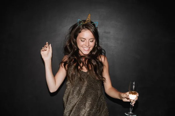 Image of young smiling woman holding glass of champagne while dancing — Stock Photo, Image