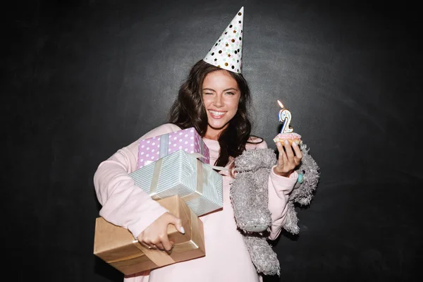 Obraz uśmiechniętej kobiety trzymającej pudełka z prezentami i pączkami podczas mrugania — Zdjęcie stockowe