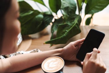 Güzel Asyalı kadın kafede cep telefonu kullanarak oturuyor..