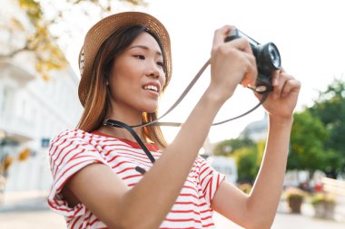 Asyalı turist kadının portresi retro kamerayla çekiliyor.