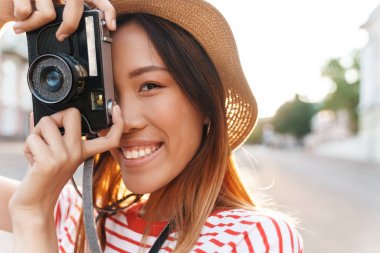 Asyalı turist kadının portresi retro kamerayla çekiliyor.