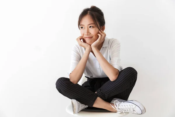 Lächelnde junge asiatische Frau im lässigen Outfit sitzend — Stockfoto