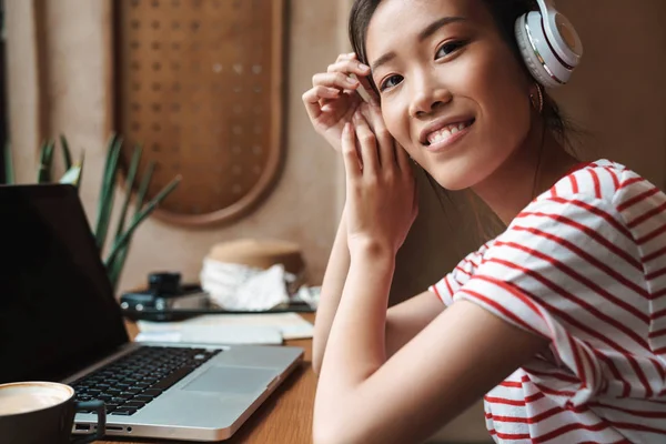 Porträt einer lächelnden asiatischen Frau mit Kopfhörer und Laptop — Stockfoto