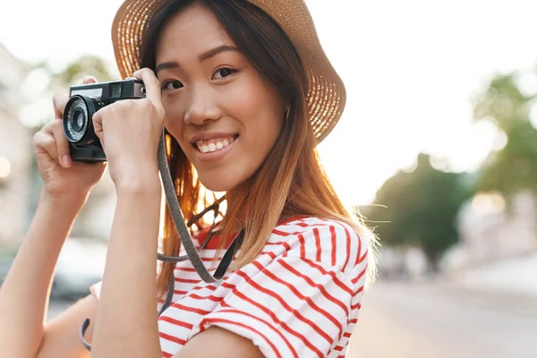 Asyalı turist kadının portresi retro kamerayla çekiliyor.