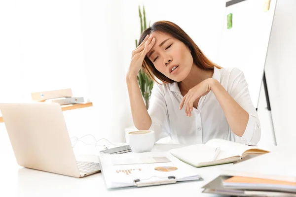 Image of sick asian businesswoman touching her forehead in offic — 图库照片