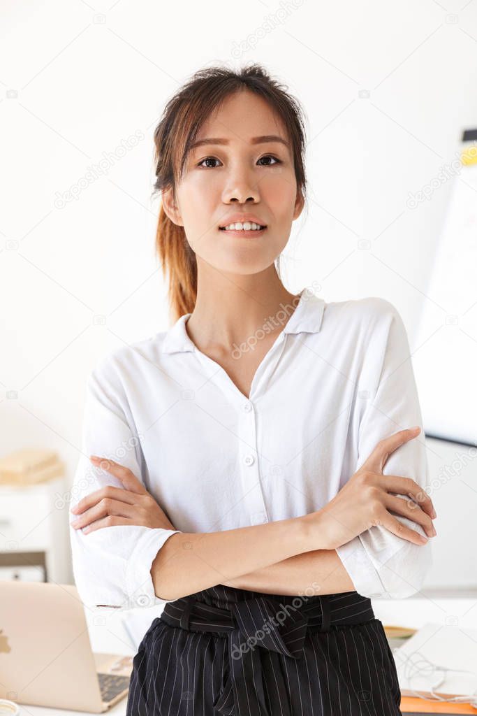 Confident attractive young asian businesswoman standing at her office