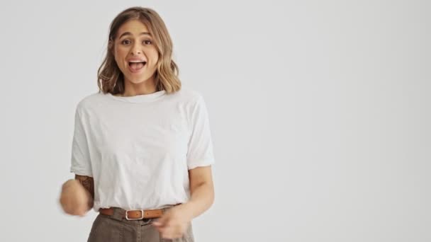 Gelukkig Jonge Vrouw Dragen Basic Shirt Wijzend Naar Zijkant Geïsoleerd — Stockvideo