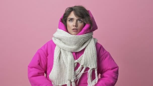 Dissatisfied young woman wearing a winter jacket with a scarf is crossing her hands isolated over a pink background — Stock Footage Dissatisfied Young Woman Wearing Winter Jacket Scarf Crossing Her Hands Stock Footage