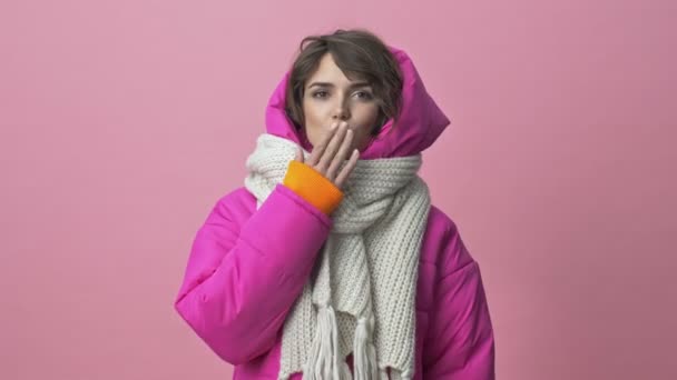 Cute young woman wearing a winter jacket with a scarf is sending an air kiss to the camera isolated over a pink background — Stock Footage Cute Young Woman Wearing Winter Jacket Scarf Sending Air Kiss Royalty Free Stock Video
