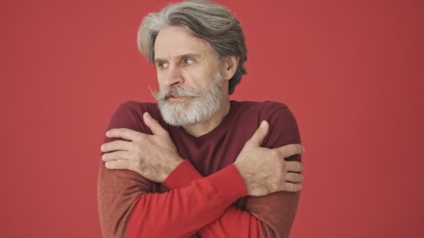 Erstarrter Grauhaariger Bärtiger Mann Roten Pullover Umarmt Sich Während Zeigt — Stockvideo