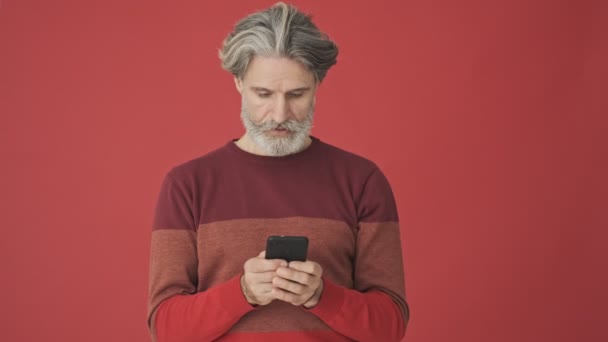 Ein Älterer Grauhaariger Mann Roten Pullover Der Sein Smartphone Über — Stockvideo