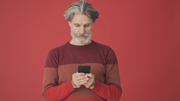 Focused Elder Gray Haired Bearded Man Red Sweater Using Smartphone — Stock Video