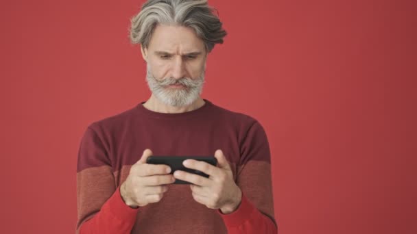 Displeased Bored Gray Haired Bearded Man Red Sweater Using Smartphone — Stock Video