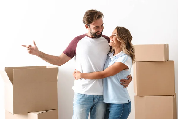 Foto de pareja feliz abrazando y señalando con el dedo a un lado — Foto de Stock