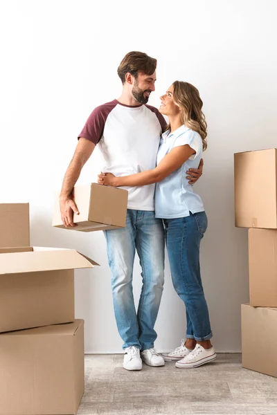 Foto de pareja sonriente abrazando y sosteniendo la caja de cartón — Foto de Stock