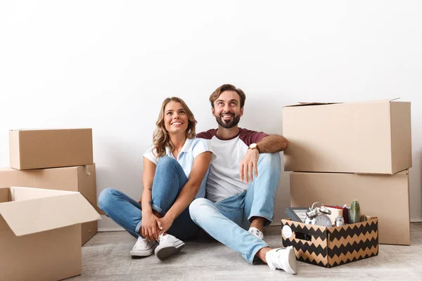 Photo of smiling couple looking upward while sitting cardboard boxes — 스톡 사진