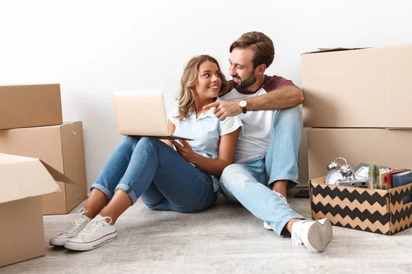 Foto de pareja usando y apuntando con el dedo a la computadora portátil mientras está sentado — Foto de Stock