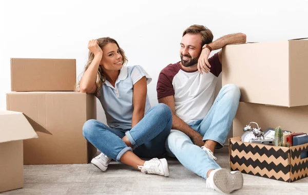 Photo of smiling couple looking at each other sitting near boxes — 스톡 사진