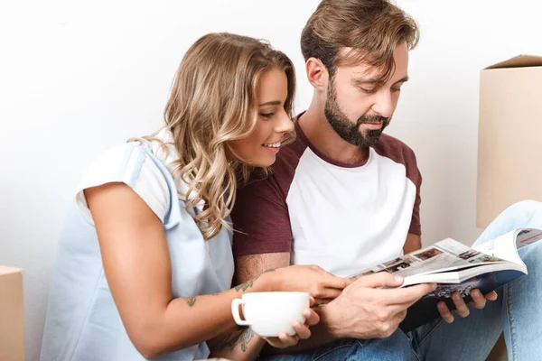 Foto de pareja bebiendo café y leyendo la revista mientras está sentada — Foto de Stock