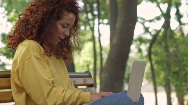 Egy Csinos Fiatal Vonzó Göndör Vörös Hajú Használja Laptopját Miközben — Stock videók