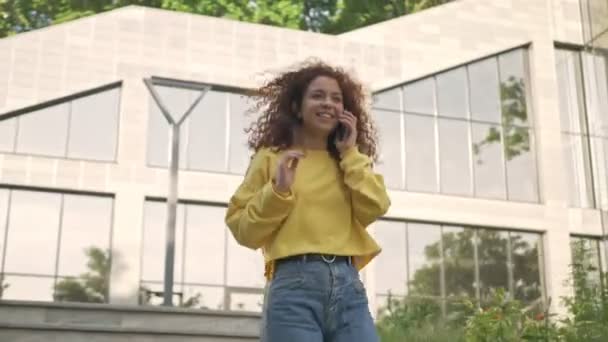 Kıvırcık Saçlı Çekici Genç Bir Kadın Telefonda Modern Bir Binanın — Stok video