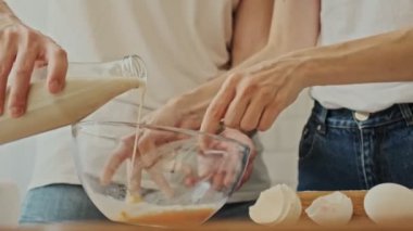 Genç bir çiftin kahvaltı hazırlarken ve evde hamuru karıştırırken yakın plan görüntüsü.