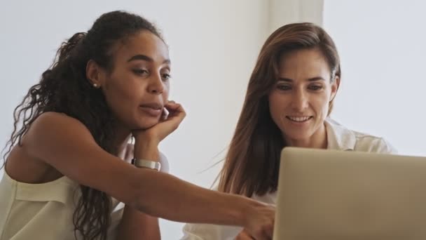 Gülümseyen Genç Bayan Meslektaşlar Ofiste Otururken Dokümanlarla Çalışıp Dizüstü Bilgisayar — Stok video